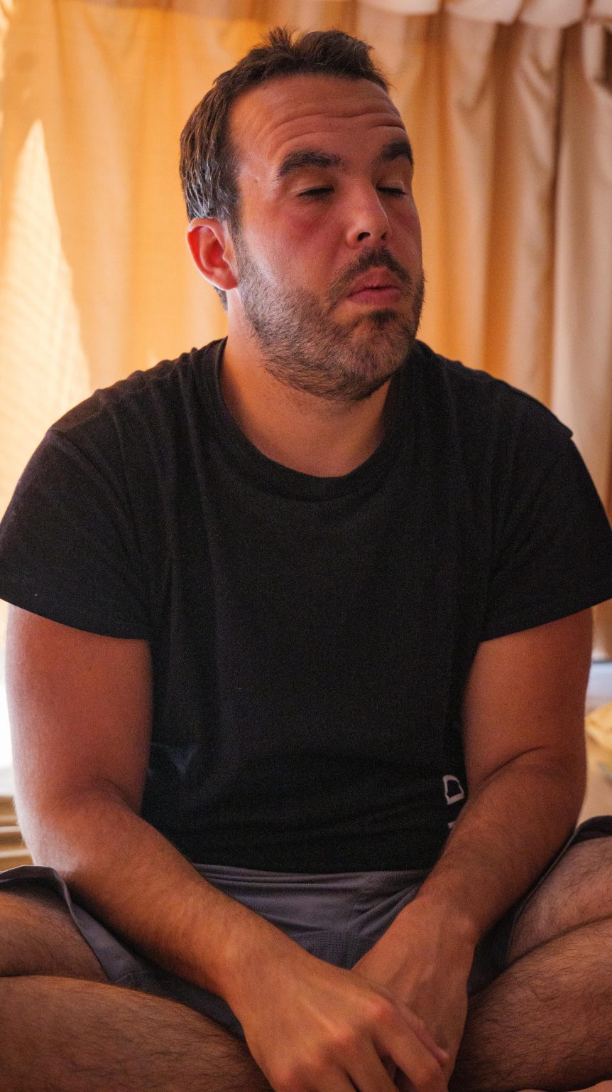 Rubén sentado en el suelo con posición de meditación con los ojos cerrados